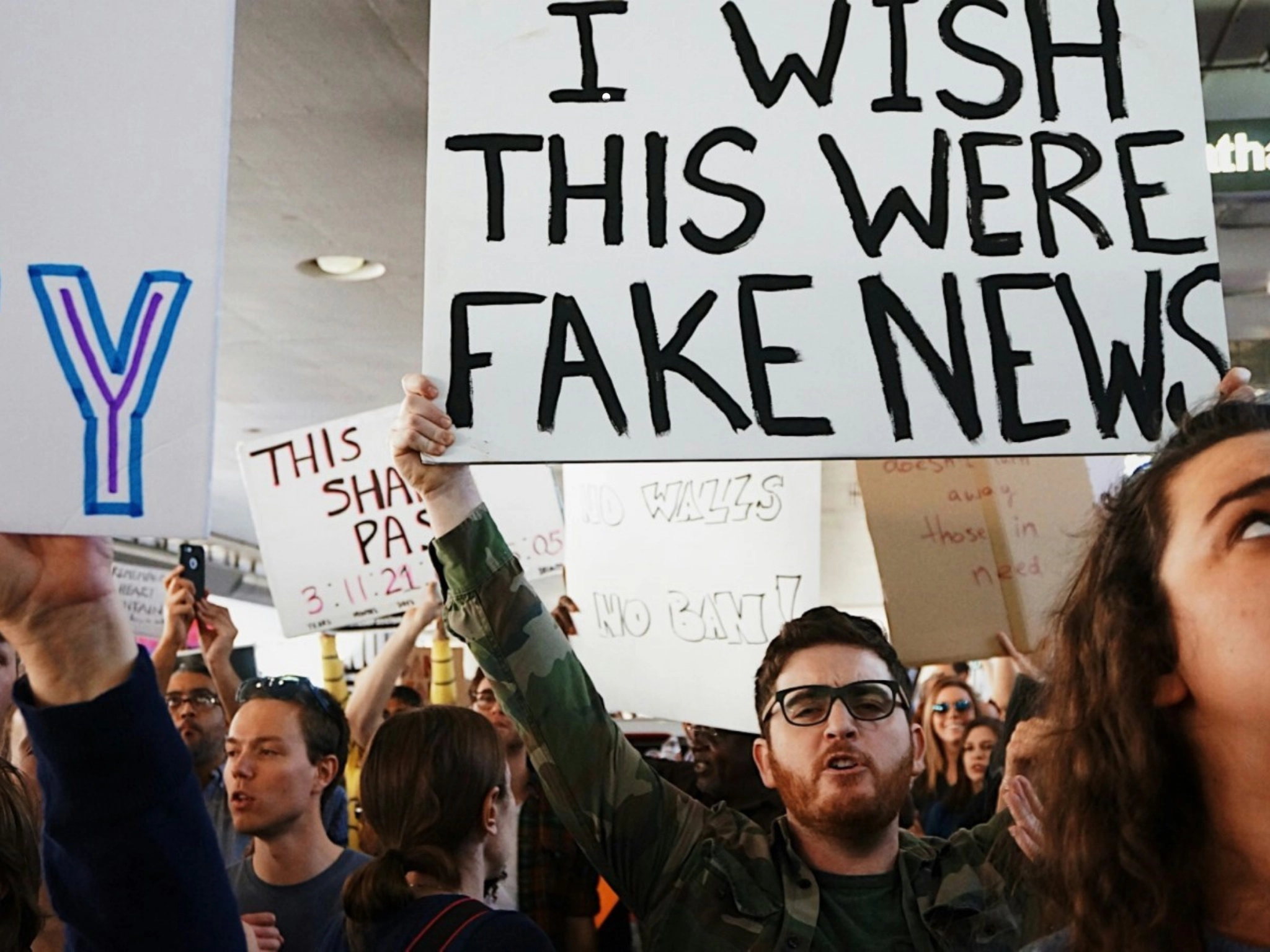 Demonstration mit Plakat „I wish this were fake news“ in Menschenmenge