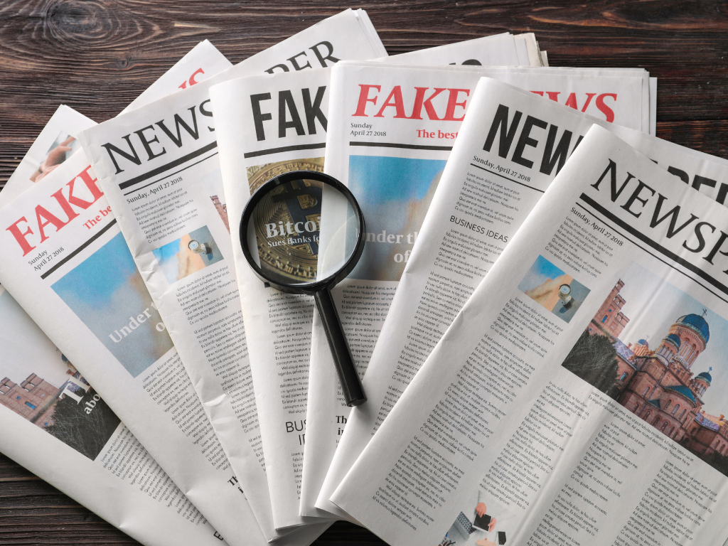 Symbolbild Fake News: Zeitungen mit Schlagzeilen und Lupe als Zeichen für Medienanalyse und Desinformation